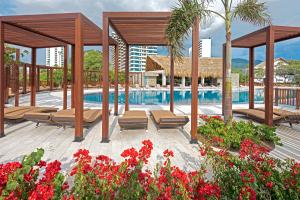 圣玛尔塔Apartasuites Samaria - Club de Playa的一个带长椅和鲜花的游泳池的度假酒店
