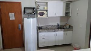 热河市Águas da Serra Apart Hotel的白色的厨房配有冰箱和微波炉。