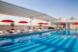 迪拜迪拜汽车城丽柏酒店的一座大楼内的游泳池,配有红色遮阳伞