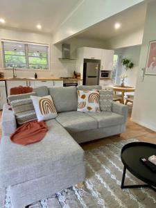 马莱尼Maleny Lake Cottages的一间带灰色沙发的客厅和一间厨房