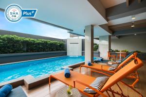 曼谷Alt Hotel Nana by UHG的一座带橙色家具的别墅内的游泳池