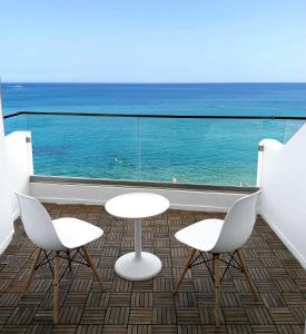 赫索尼索斯Azure Mare Hotel的阳台上摆放两把椅子和两张桌子,