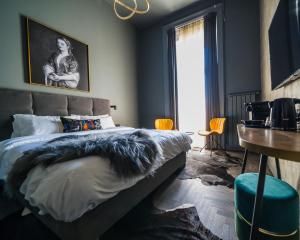 布达佩斯Leo Boutique Rooms - Adults Only的一间卧室配有一张床、一张书桌和一个窗户。