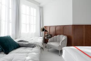苏黎世Ruby Mimi Hotel Zurich的一间卧室配有一排床和一把椅子