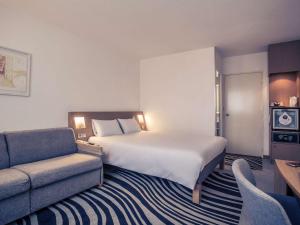 布尔日布尔吉诺富特酒店的酒店客房设有一张大床和一张沙发。