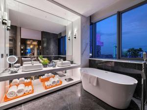 西安西安西咸诺富特酒店的带浴缸和两个盥洗盆的浴室以及大窗户。