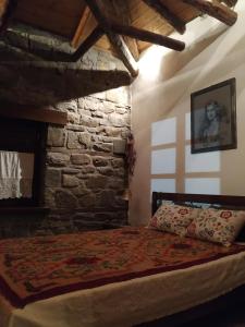 VláchaΠαραδοσιακή πέτρινη κατοικία στην Βλάχα Ελάτης的一间卧室设有一张床和石墙
