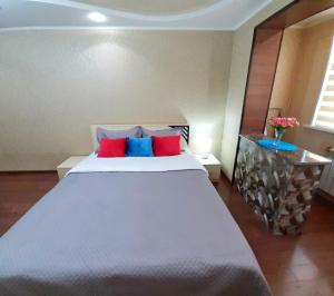 塔拉兹Уютная квартира класса ЛЮКС в городе Тараз的卧室配有白色大床和红色和蓝色枕头