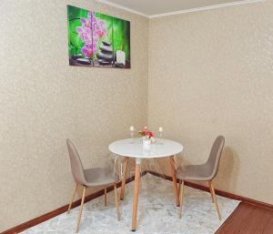 塔拉兹Уютная квартира класса ЛЮКС в городе Тараз的餐桌、椅子和墙上的绘画