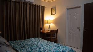 海岸角Veke Executive Lodge & Event Center的一间卧室配有一张床和一张带台灯的书桌