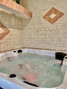 圣耐克森Suite Privative Jacuzzi Sauna de la Villa Del Castagnol的石墙旁的浴缸