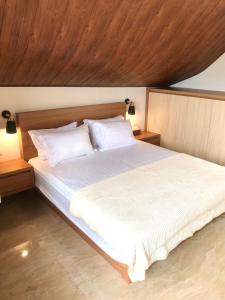 茂物Vimala Hills Villa 4 Bedroom with Mountain View的卧室配有一张白色大床和木制天花板