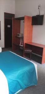 普诺科罗尼尔广场酒店的一间卧室配有蓝色的床和一张书桌