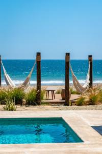 洛斯拉甘斯Norte Suites Boutique的一个带游泳池和吊床的度假胜地和海滩