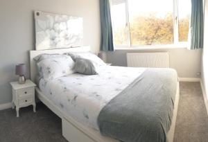 特伦特河畔斯托克Cosy 3 bedroom residential house, private garden, 30 minutes from Alton Towers, 5 minute walk to Trentham Gardens.的卧室配有白色的床和窗户