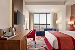埃里温Ramada Hotel & Suites by Wyndham Yerevan的酒店客房配有一张床和一张书桌及一台电视