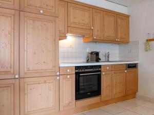 采尔马特Apartment Roger-2 by Interhome的厨房配有木制橱柜和黑烤箱。