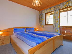 PankrazbergApartment Untererhof-1 by Interhome的一间卧室配有一张带蓝色床单的床和一扇窗户。