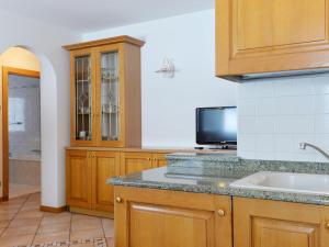 坎皮泰洛Apartment Ardoney-1 by Interhome的一间带木制橱柜和水槽的厨房以及一台电视。