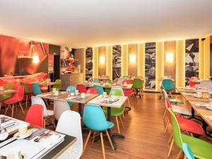 萨尔布吕肯萨尔布吕肯宜必思酒店的一间餐厅,房间内设有桌子和五颜六色的椅子