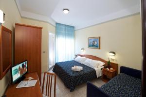 卡托利卡Hotel Queen Mary的酒店客房配有一张床铺和一张桌子。