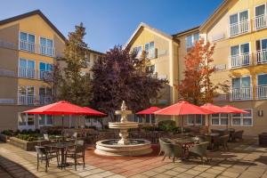 西雅图福朋喜来登西雅图市中心酒店的庭院配有桌椅和红色遮阳伞。