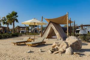 阿布扎比Bab Al Nojoum Hudayriyat Camp的沙滩上的帐篷和两把椅子