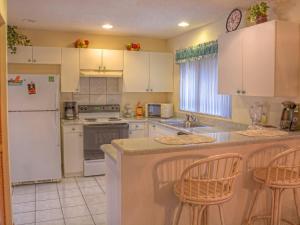 棕榈海岸Holiday Home Sunrise by Interhome的厨房配有白色家电和2张酒吧凳