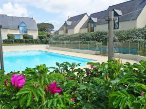 KervozApartment Les Villas de Kermaria by Interhome的游泳池位于一些粉红色花房前