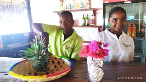 Unguja UkuuMenai Bay Beach Bungalows的两个人站在桌子边,一边拿着一碗鲜花