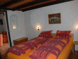 AquilaHoliday Home Rustico Cristallo by Interhome的一间卧室配有两张带红色和橙色枕头的床