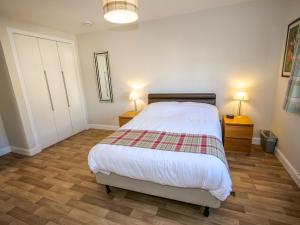 金罗斯Holiday Home Devonvale Place by Interhome的一间卧室配有一张床、两个床头柜和两盏灯。