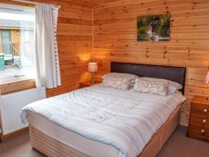 金罗斯Chalet Osprey Lodge by Interhome的卧室配有木墙内的一张床