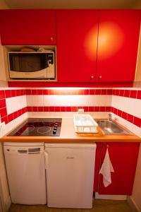 拉普拉涅1800Le Panoramix的厨房配有红色橱柜、水槽和微波炉