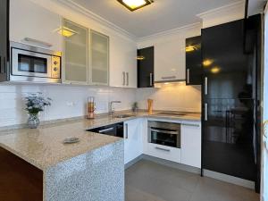 埃利松多Apartamento Baztán的厨房配有白色橱柜和黑色冰箱。