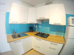 科武港Ahoy Porto Covo Hostel的厨房配有白色橱柜、水槽和冰箱。