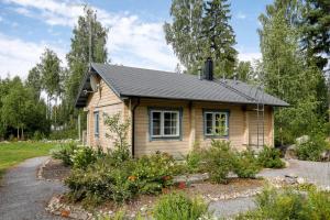 SysmäCottage Kivitatti的一座小木房子,前面设有一个花园