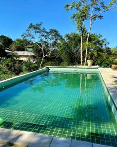 布希奥斯Recanto da Ferradura的后院的无边游泳池,铺有绿色瓷砖
