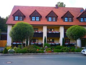 欧波楚巴赫德里林登旅馆的一座有红屋顶的房屋,上面有鲜花和树木