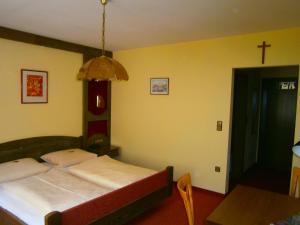 欧波楚巴赫德里林登旅馆的卧室配有一张床,墙上有十字架