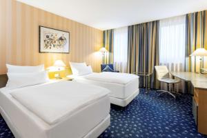 维也纳NH多瑙城酒店的酒店客房配有两张床和一张书桌