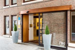 梅赫伦NH梅赫伦酒店的通往砖砌建筑的敞开的门,砖砌有两株盆栽植物