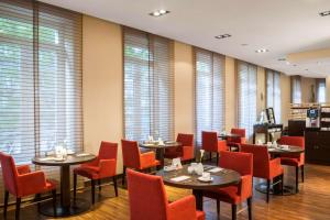 杜塞尔多夫NH杜塞尔多夫国王大道酒店的餐厅设有桌子和红色椅子以及窗户。