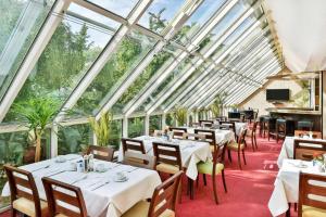 贝河畔的海尔斯伯格海德堡海尔斯伯格NH酒店的餐厅设有白色的桌椅和玻璃天花板。