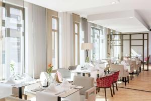 纽伦堡纽伦堡NH系列城市的餐厅设有白色的桌椅和窗户。