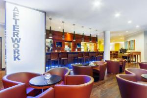 布达佩斯NH布达佩斯市酒店的一间带桌椅的餐厅和一间酒吧