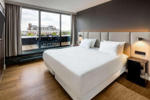 阿姆斯特丹阿姆斯特丹卡兰萨NH酒店的一张大白色的床,位于一个设有大窗户的房间