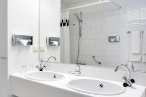 赞德沃特赞德沃特NH酒店的白色的浴室设有两个盥洗盆和镜子