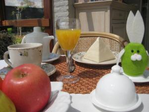 Overpelt会泽贝克斯住宿加早餐旅馆的一张桌子,上面放着苹果和一杯橙汁