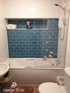 特雷杜尔Rhodri Apartment with Sea Views and Sun Terrace的带浴缸的浴室和蓝色瓷砖墙
